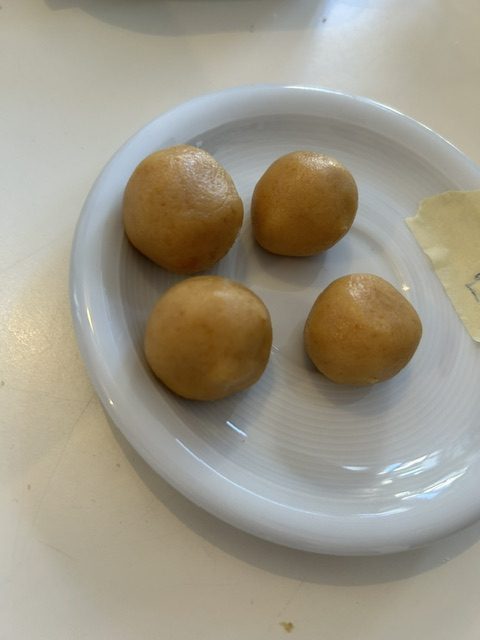Vier runde Teigkugeln für Cakepops liegen auf einem weißen Teller