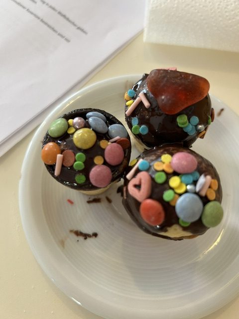 Fertige Schoko-Muffins mit bunten Streuseln und Zuckerdeko auf einem Teller